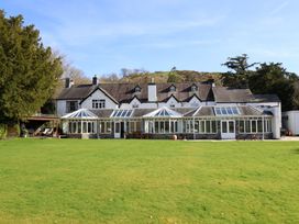A house with a conservatory and lawn at Plas Dolguog in Machynlleth