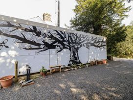 A mural of a tree on a wall with plants and gravel at Plas Dolguog Machynlleth