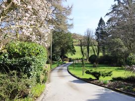 A driveway lined with trees and flowering plants at Plas Dolguog in Machynlleth