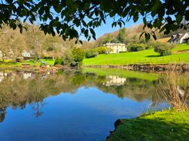 A lake with reflections of houses and trees at Lakeview Villa near Liskeard