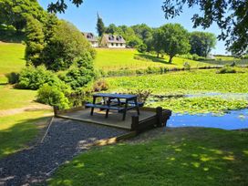 A deck with a picnic table near a pond at Lakeview Villa near Liskeard
