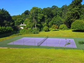 A tennis court surrounded by trees and grass at Lakeview Villa near Liskeard