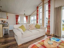 A living room with a sofa, table, and windows at 8 Summerleaze in Bude