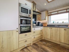 A kitchen with cabinets, oven, microwave, and sink at 8 Summerleaze, Bude