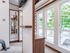 A bedroom with a wall-mounted television and windows at Fern View -Kelling Heath Holiday Park in Weybourne near Sheringham