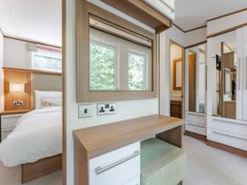 A bedroom with a bed, chair, and mirror at Fern View -Kelling Heath Holiday Park in Weybourne near Sheringham