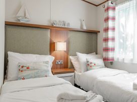 A bedroom with two beds and a lamp at Fern View -Kelling Heath Holiday Park in Weybourne near Sheringham