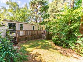 A wooden deck with steps leading to a trailer in a wooded area at Fern View -Kelling Heath Holiday Park Weybourne near Sheringham