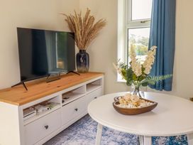 A living room with a television and flowers on a coffee table at Flat 5 in Looe