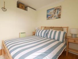 A bedroom with a striped bed and bedside table at Flat 5 in Looe