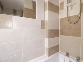 A bathroom with wall tiles and a bath tub at Flat 5 in Looe