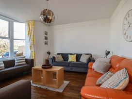 A living room with sofas, a coffee table, and a wall clock at Sea View in Newquay