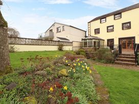 A garden with flowers and a house in the background at High Mill House Penrith