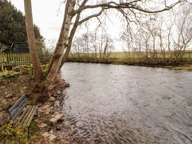 A river with trees and a bench at High Mill House in Penrith