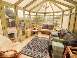 A conservatory with seating and a rug at High Mill House Penrith