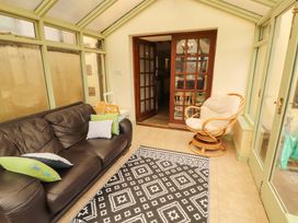 A conservatory with a couch and dining table at High Mill House in Penrith