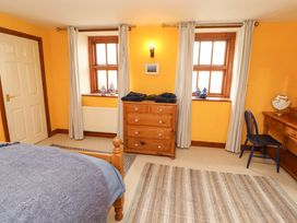 A bedroom with wooden furniture and windows at High Mill House in Penrith
