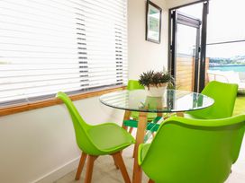 A dining room with glass table and green chairs at La Casita Newquay