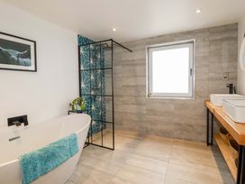A bathroom with a bathtub, shower, and sink at La Casita in Newquay