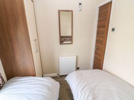 A bedroom with two beds and a wardrobe at 37 Horizon Park in Hartlepool