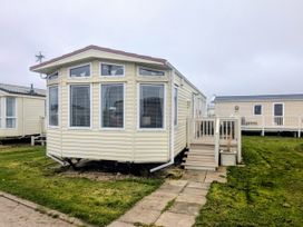 A caravan with a deck and grass pathway at Lynsey's Coastfields Caravan in Skegness