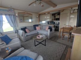 A living room with sofa, coffee table, and dining area at Lynsey's Coastfields Caravan in Skegness
