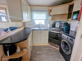 A kitchen with sink, oven and washing machine at Lynsey's Coastfields Caravan in Skegness