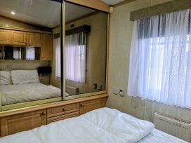 A bedroom with a bed and a mirror at Lynsey's Coastfields Caravan in Skegness