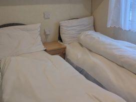 A bedroom with two beds and a bedside table at Lynsey's Coastfields Caravan in Skegness