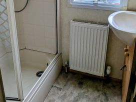 A bathroom with a shower, sink, and radiator at Lynsey's Coastfields Caravan, Skegness