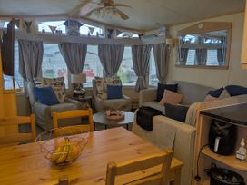 A living room with a sofa, table, and chairs at Lynsey's Coastfields Caravan in Skegness