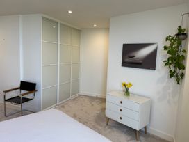 A bedroom with a bed, chair, dresser and closet at Apartment 29 in Newquay