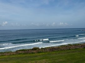 A view of the ocean with surfers and a stone wall at Apartment 29 in Newquay