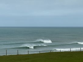 An ocean with waves and surfers near a grass area at Apartment 29 Newquay