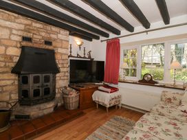 A living room with stone fireplace and television at The Annexe at Cherry Cottage Upton St Leonards