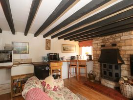 A living room with a fireplace and kitchen counter at The Annexe at Cherry Cottage Upton St Leonards