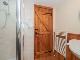 A bathroom with a shower and wooden door at The Annexe at Cherry Cottage Upton St Leonards