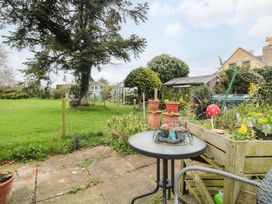 A garden with a table and planters at The Annexe at Cherry Cottage in Upton St Leonards