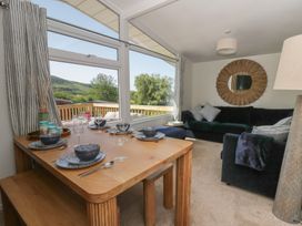 A dining area with a table set for meals and a sofa at Chalet 47 Erw Porthor Tywyn