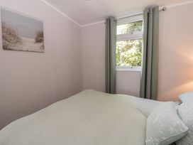 A bedroom with a bed and window at Chalet 47 Erw Porthor Tywyn