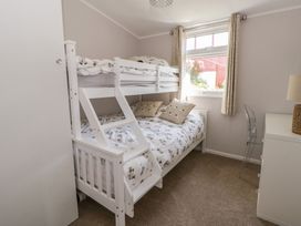 A bedroom with a bunk bed and a single bed at Chalet 47 Erw Porthor in Tywyn