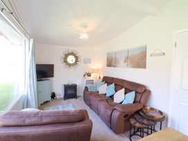 A living room with a sofa and television at Chalet 23 Erw Porthor Tywyn