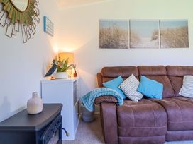 A living room with a sofa, pillows and a lamp at Chalet 23 Erw Porthor in Tywyn