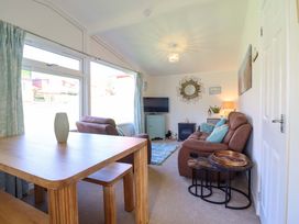 A living room with a table, sofa, and television at Chalet 23 Erw Porthor Tywyn