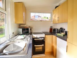 A kitchen with appliances and cupboards at Chalet 23 Erw Porthor in Tywyn