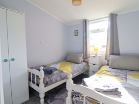 A bedroom with two beds and a wardrobe at Chalet 23 Erw Porthor Tywyn