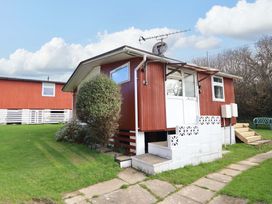 An outdoor view of a red house with steps and a garden at Chalet 23 Erw Porthor Tywyn