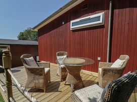 A patio area with wicker furniture and a glass table at Chalet 23 Erw Porthor Tywyn