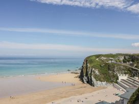 A beach with people and cliffs at 62 Golf Lodges in Atlantic Reach near Fraddon