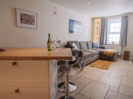 A living room with a sofa and bar stool at Phoenix Cottage in Lyme Regis